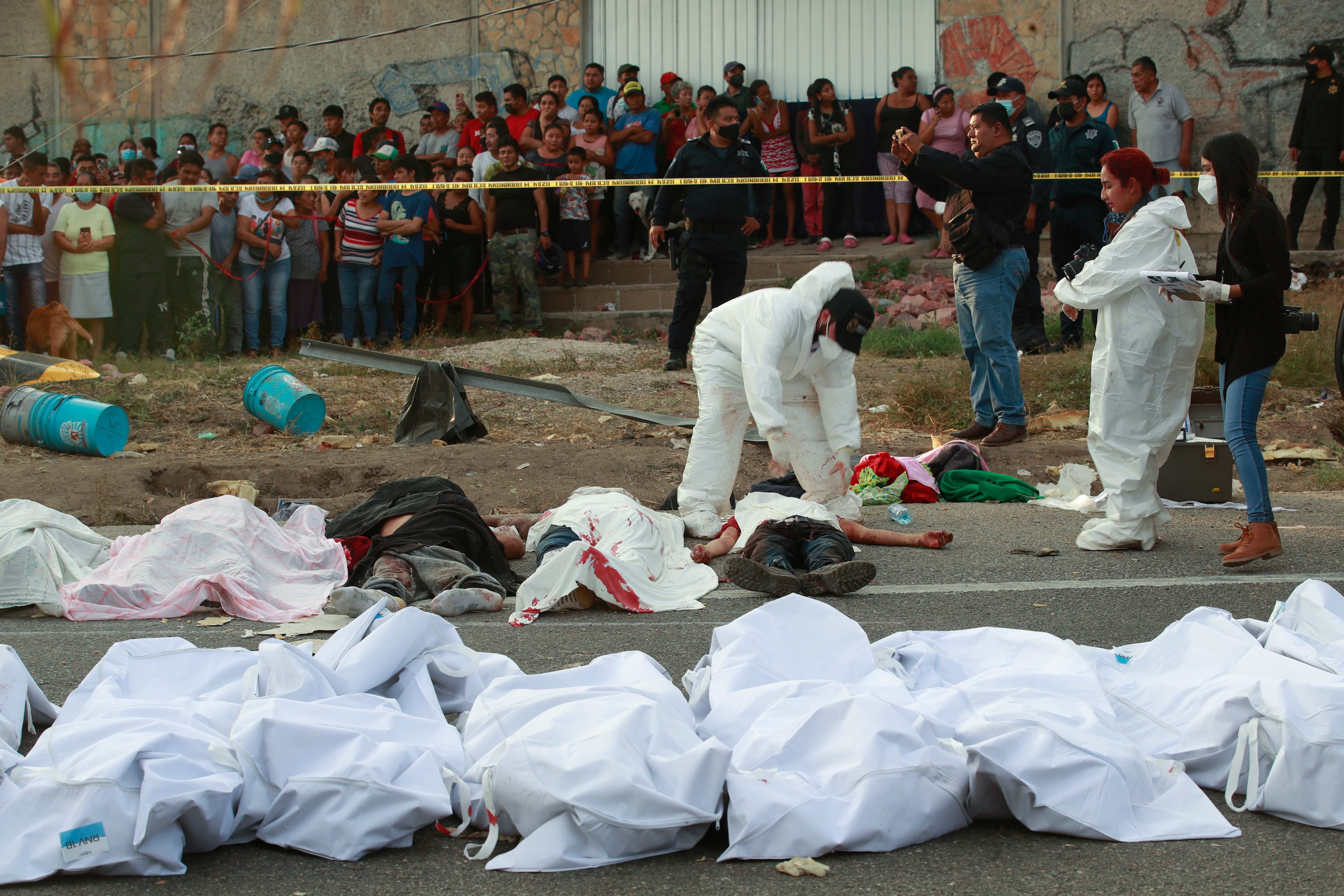 Bodies in bags sit on the side of the road after a deadly semi-trailer truck crash in Tuxtla Gutierrez, Chiapas state, Mexico, Dec. 9, 2021.